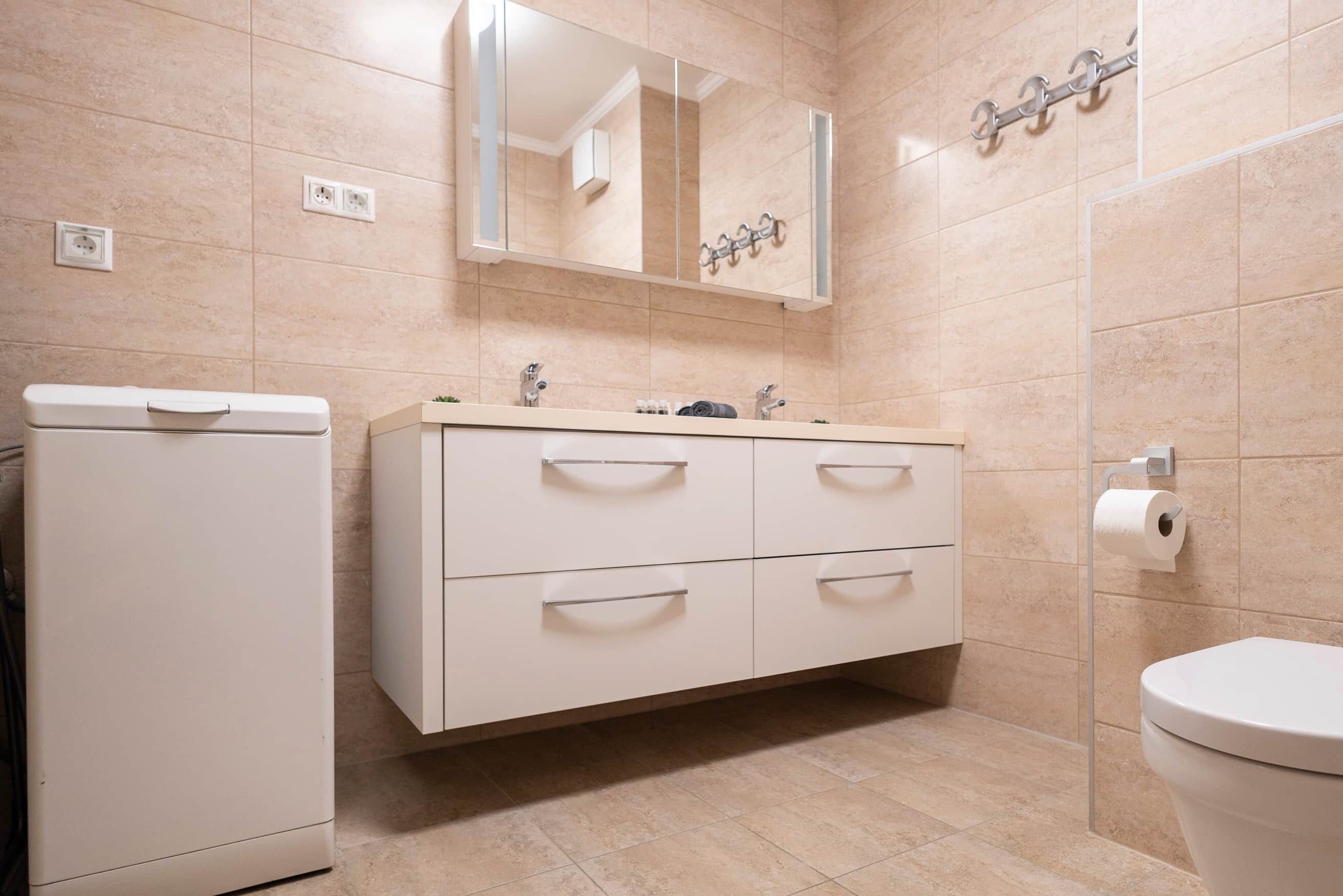 A bathroom with a white vanity, a mirror, a toilet, and a towel rack.