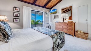 Een slaapkamer met een bed, een dressoir, een spiegel en uitzicht op de omgeving door een schuifdeur.