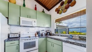 A kitchen with a white stove, green cabinets, a microwave, and a window with a view of palm trees. - Wailea Ekolu, #312 1 Bedroom Condo by RedAwning (Kihei)