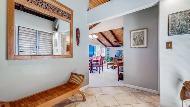 A hallway with a wooden bench, a mirror, and a dining area in the background. - Wailea Ekolu, #312 1 Bedroom Condo by RedAwning (Kihei)