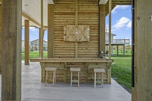 Relax in our outdoor bar area, featuring a central panel with a geometric cutout and two stools.