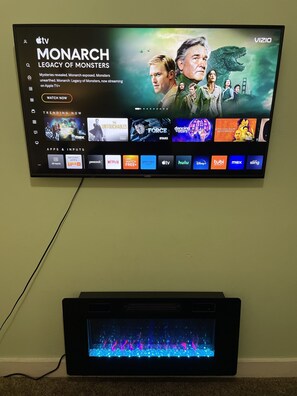 A flat-screen TV mounted on a wall displaying a streaming service interface with various content options.