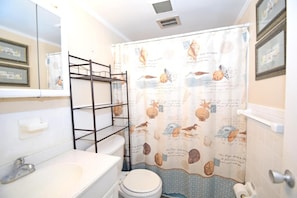Ein Badezimmer mit Toilette, Waschbecken und einer Duschkabine mit Vogel- und Muschelmuster.