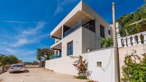 A modern two-story house with a balcony, a garage, and a white exterior wall.