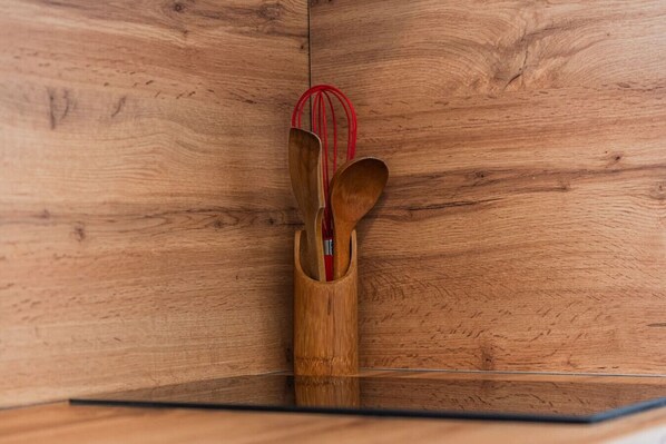Un mobiletto in legno con un cucchiaio e una frusta, entrambi con manici rossi, all'interno.