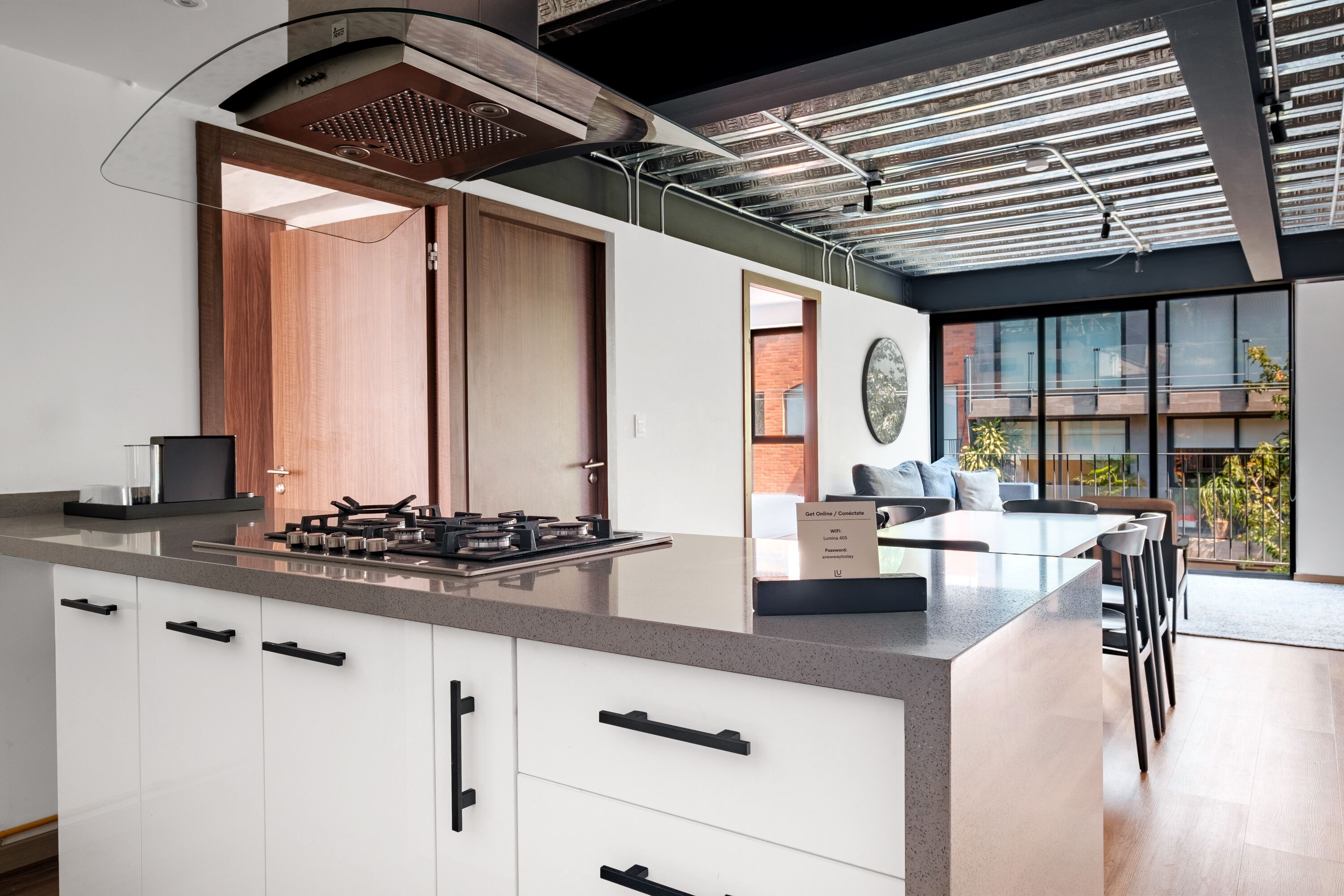 A modern kitchen with a large island, built-in appliances, and a view of the outdoor seating area.