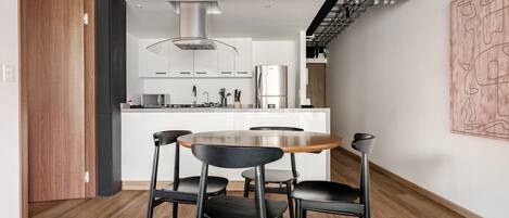 A modern kitchen with white cabinets, a stainless steel refrigerator, and a central island with a sink.