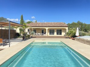 A house with a swimming pool, patio furniture, and a covered seating area.