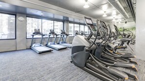 Een sportschool met loopbanden, elliptische trainers en een vloerbedekking.