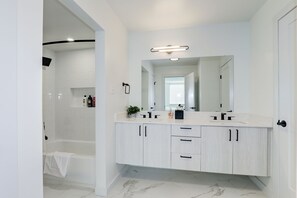 Executive appartement | Badkamer | Een bad/douchecombinatie, een haardroger, handdoeken