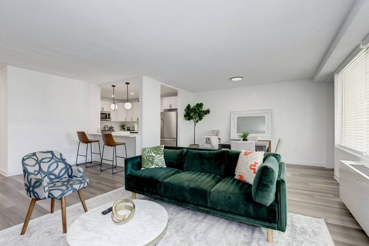 Een moderne woonkamer met een groene fluweelzitzak, een ronde salontafel en een gestreept fauteuil.