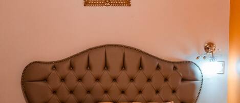 A neatly made bed with a tufted headboard, two pillows, and two folded towels.