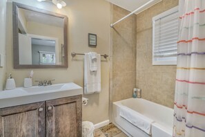 A bathroom with a sink, mirror, towel rack, and bathtub. - Cowboy Cabin (Cascade)