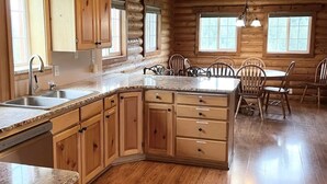 A log cabin interior with a kitchen, dining area, and wooden floors. - Jubilation Springs Cabin (Soda Springs)
