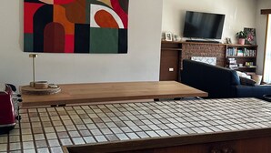 A modern kitchen with a wooden countertop, a tiled backsplash, and a hanging abstract painting. - Spacious home in Corowa’s best street right across from the Murray/pet-friendly! (Corowa)
