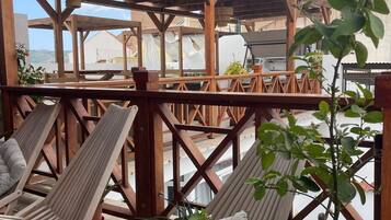 A wooden deck with two lounge chairs, a potted plant, and a view of a tower.