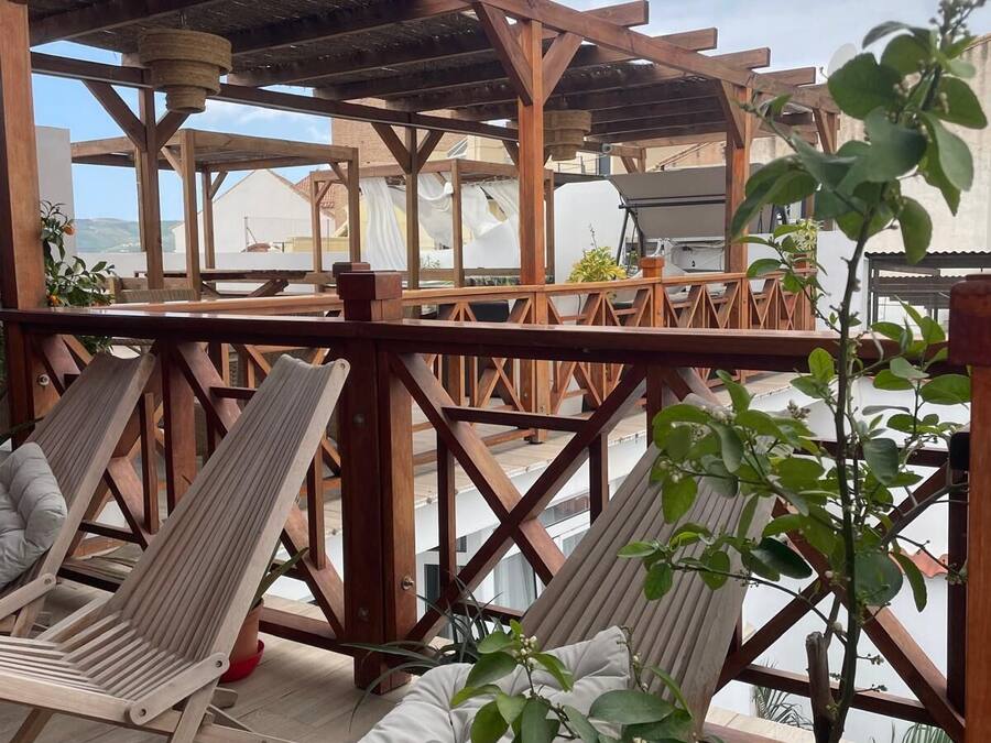 A wooden deck with two lounge chairs, a potted plant, and a view of a tower.