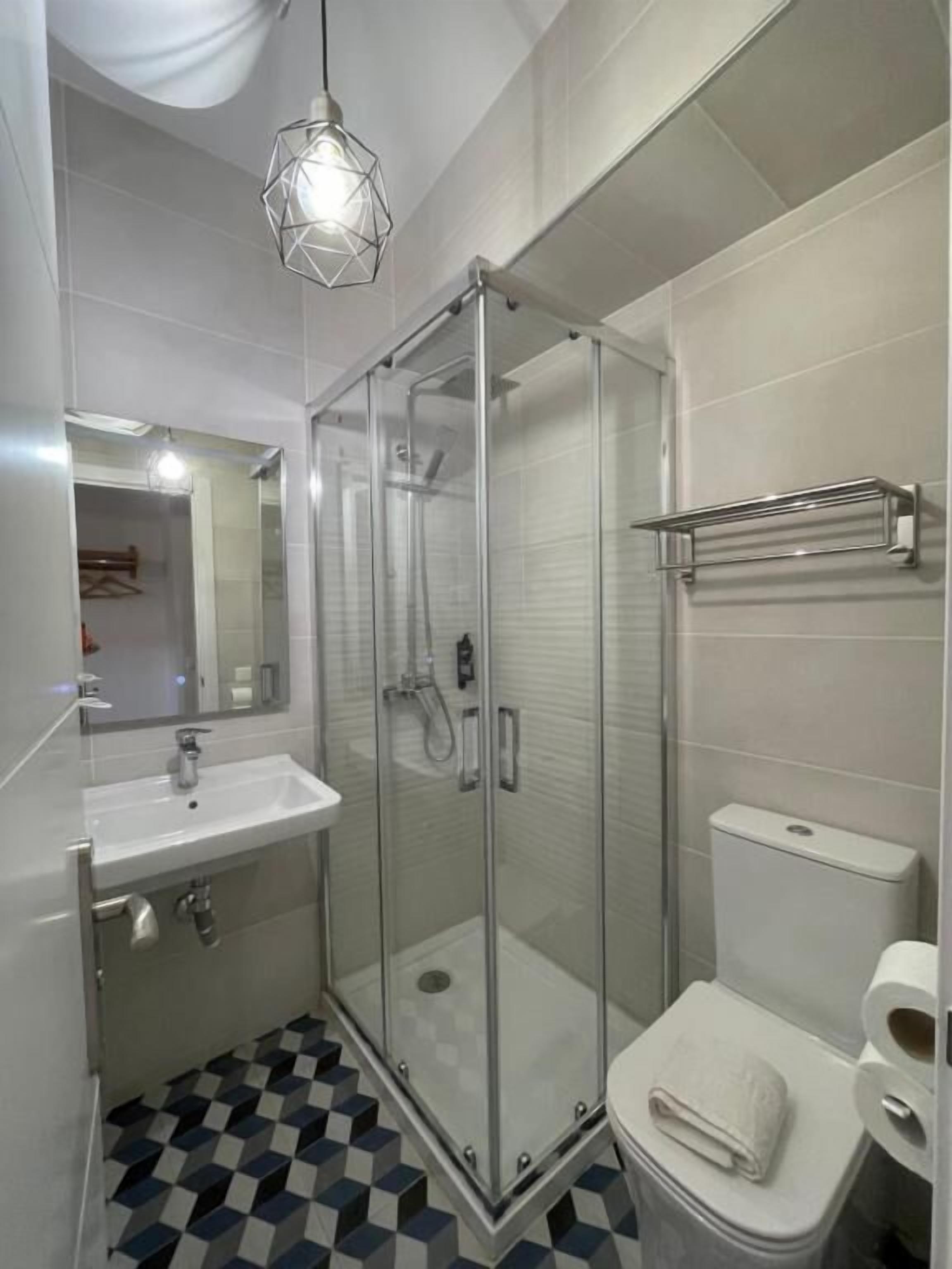 Et moderne badeværelse med brusekabine i glas, vask og toilet.