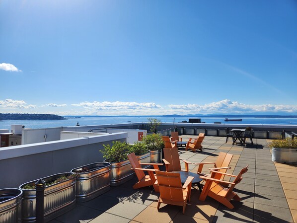 A rooftop terrace with outdoor seating, a view of the sea, and a distant cityscape. - Queen Anne Retreat ★ 1 Block from CPA! ★ Free Parking! (Seattle)