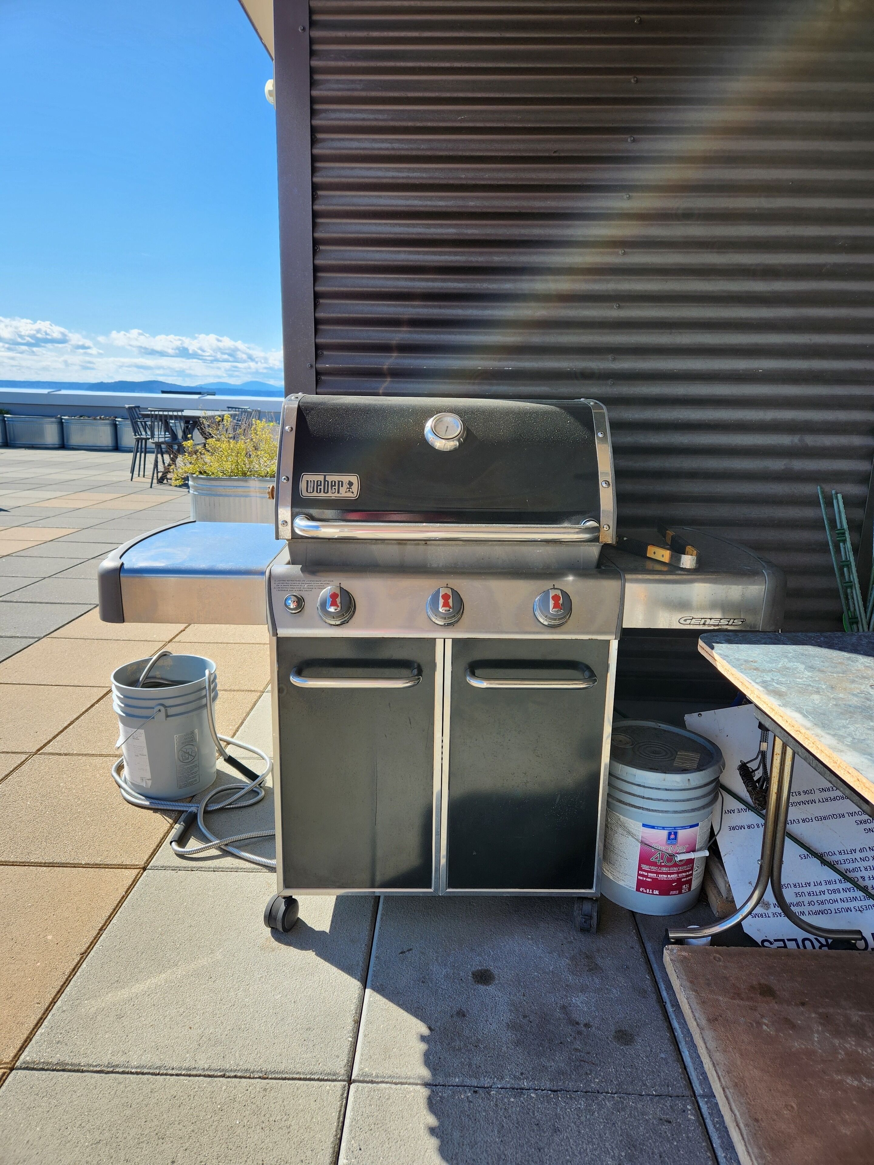 A Weber Genesis portable grill on a patio with a view of the ocean.