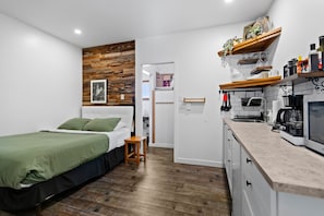 Un dormitorio con cama, mesita de noche y una pared de madera decorativa.