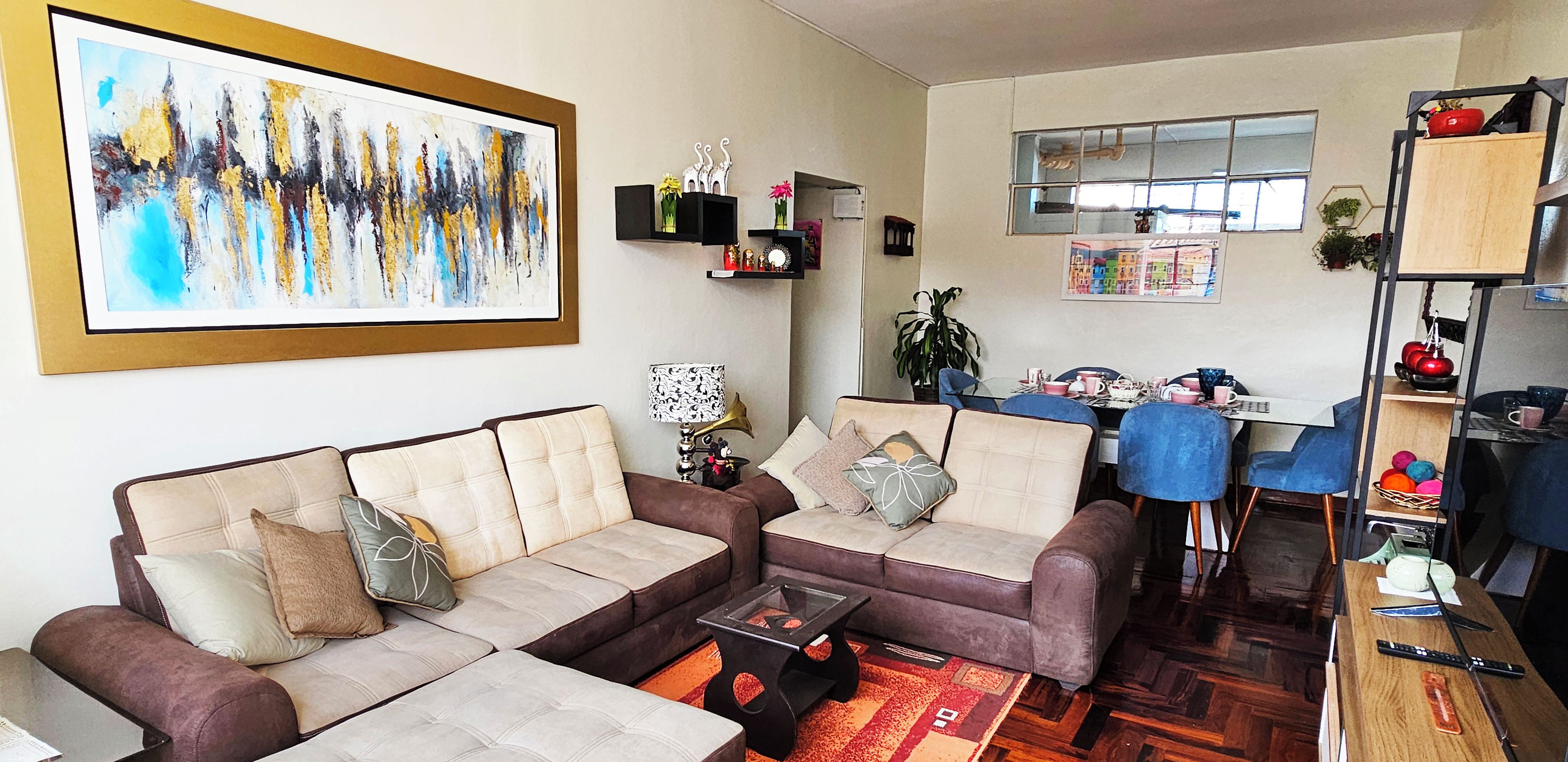Een woonkamer met een zithoek, een salontafel en een eethoek met een tafel en stoelen.