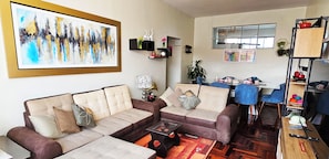 A living room with a sofa set, a coffee table, and a dining area with a table and chairs.