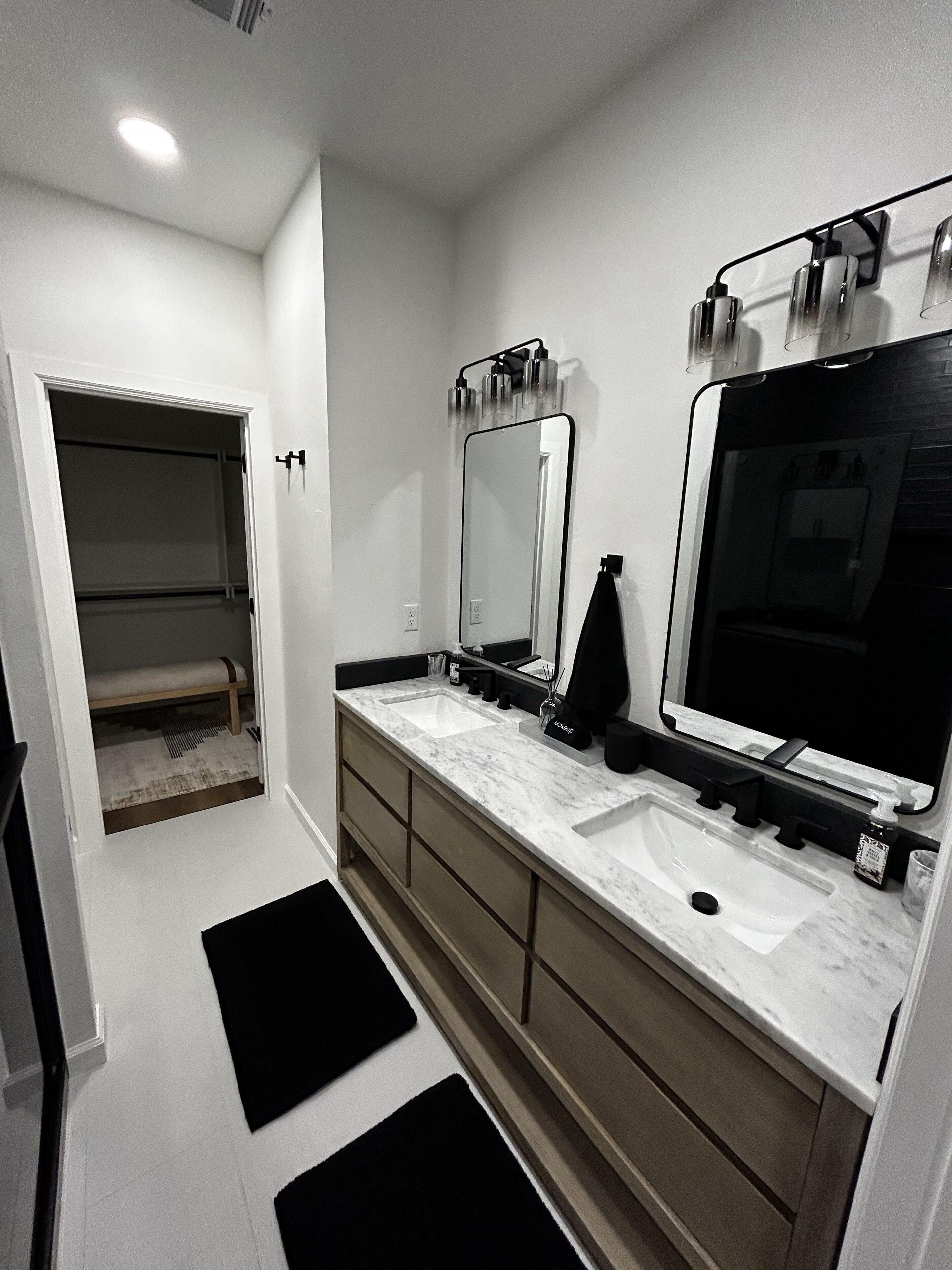 Casa de banho moderna com duas pias, um espelho grande e um closet espaçoso.