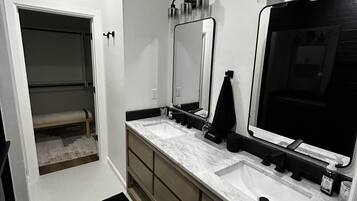 Casa de banho moderna com duas pias, um espelho grande e um closet espaçoso.