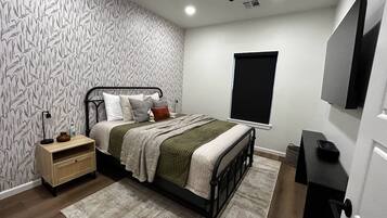 A bedroom with a bed, bedside table, lamp, and a ceiling fan.