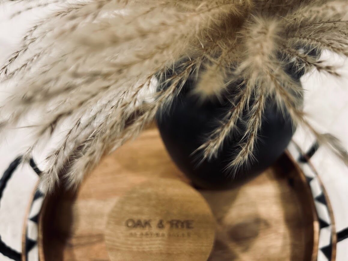 A close-up of a wooden bowl with the inscription "OAK & RYE" and a black object with white feathers on top.