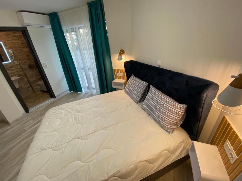 A bedroom with a bed, a nightstand, a lamp, and a sliding glass door leading to a bathroom.