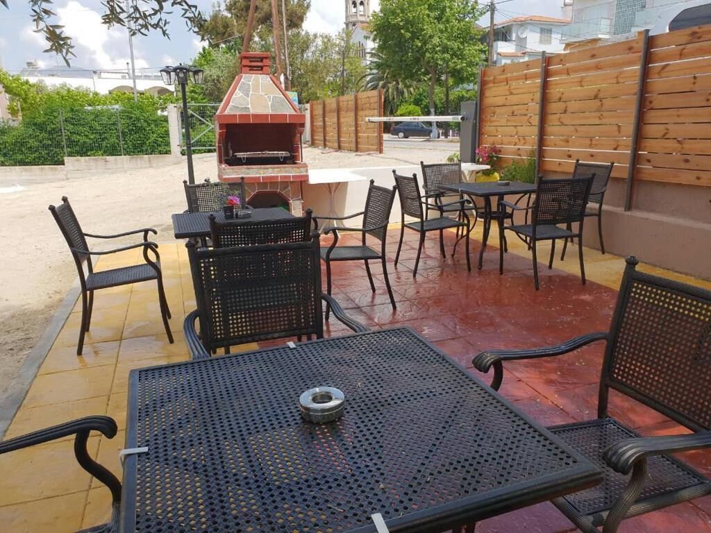 An outdoor patio area with a barbecue grill, metal tables and chairs, and a wooden fence.