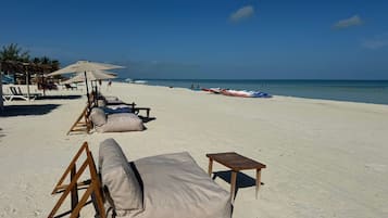 Na praia, areia branca, espreguiçadeiras