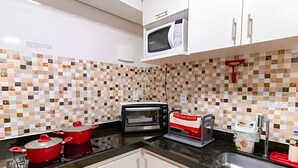 A kitchen with a microwave, toaster, red pots, and a sink. - OZPED Flats Particulares Casa Cruzeiro (Cruzeiro)