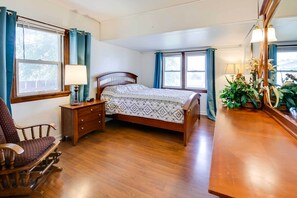 A bedroom with a wooden bed, a nightstand with a lamp, a rocking chair, a dresser, and a mirror. - Welcome Families & Pets, walk to town, Torrrington, WY retreat (Torrington)