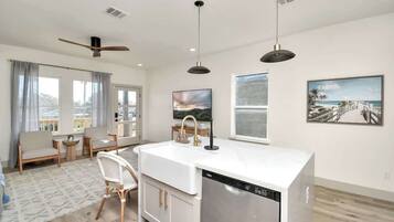A modern kitchen with a dishwasher, a dining area with a table and chairs, and a large window with a view.