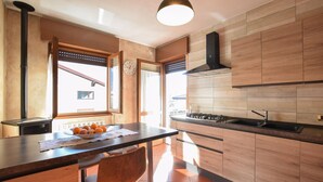 Una cocina moderna con armarios de madera, una estufa negra y un ventanal con vistas al exterior.