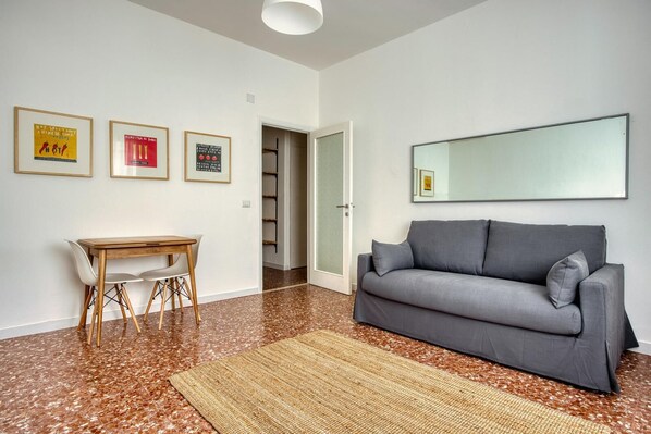 A modern living room with a grey sofa, wooden coffee table, and framed pictures on the wall. - Two Bedroom Apartment (ROMA)