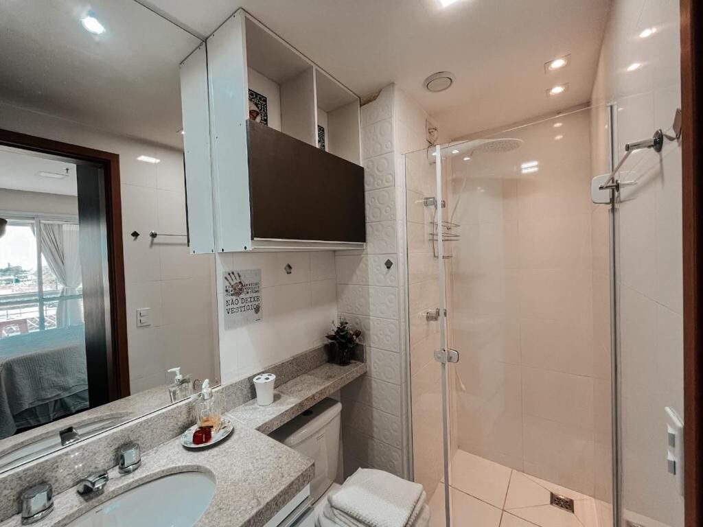A modern bathroom with a glass shower enclosure, a sink with a marble countertop, and a vanity with a mirror.