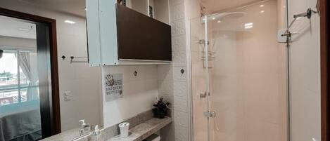 A modern bathroom with a glass shower enclosure, a sink with a marble countertop, and a vanity with a mirror.