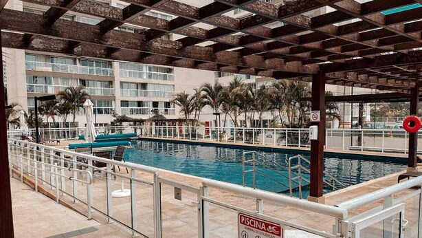 Une piscine intérieure dotée d’un panneau de sécurité, de chaises longues et d’un espace abrité avec un plafond en bois.