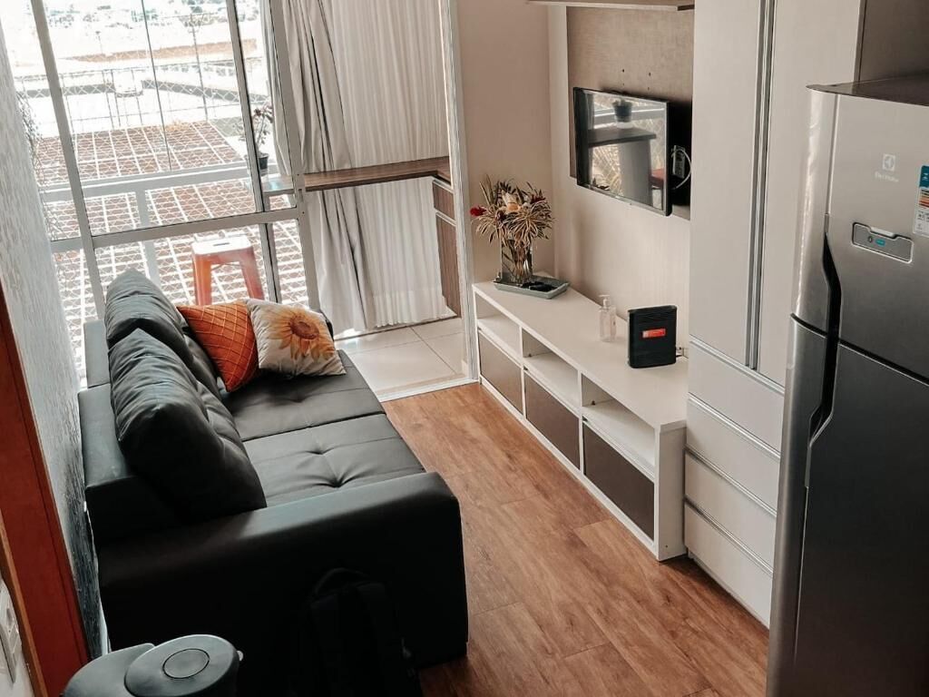 A modern kitchen with a built-in refrigerator, a white countertop, and a black sofa with cushions.