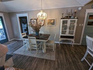 A dining area with a chandelier, a white cabinet with glass doors, and a dining table set for four. - Robbins Nest Toledo Bend, Waterfront Getaway - Lakeside is best at the Robbins Nest! (Burkeville)