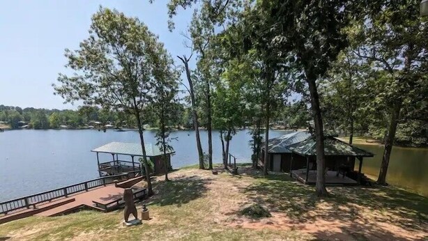 A lakeside property with a dock, a covered seating area, and a cabin.