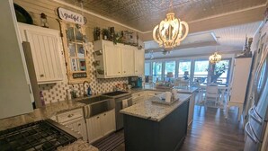 A spacious kitchen with a large island, white cabinetry, and a chandelier.