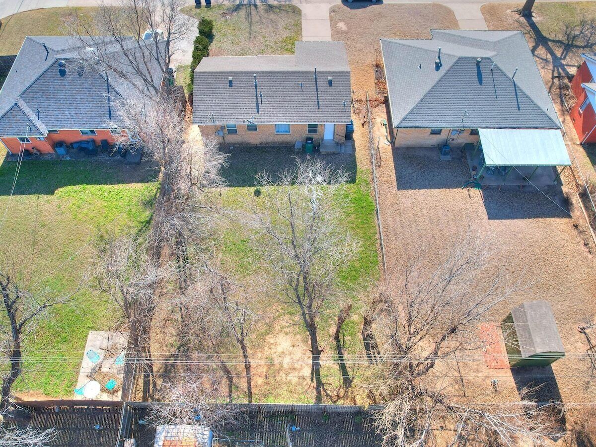 Vista aerea di una zona residenziale con diverse case, un cortile recintato e alcuni alberi.