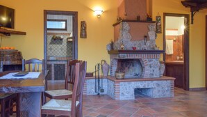 A cozy living area with a fireplace, a dining table with chairs, and a television.