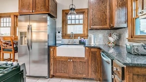A kitchen with wooden cabinets, a stainless steel refrigerator, a sink, and a window.
