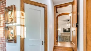 A hallway with a white door, wooden steps, and a kitchen area in the background.